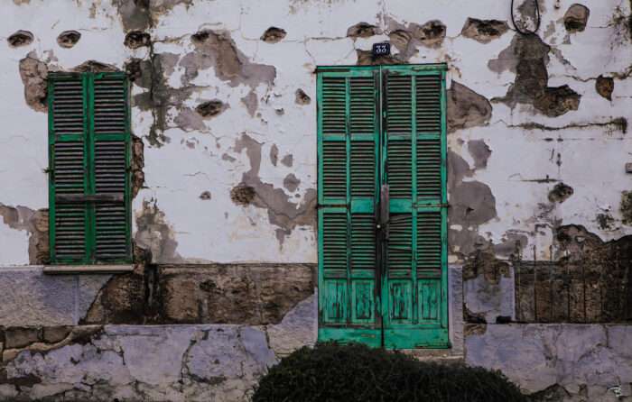 Verfallene Fassade eines Dorfhauses mit geschlossenen Persianern.